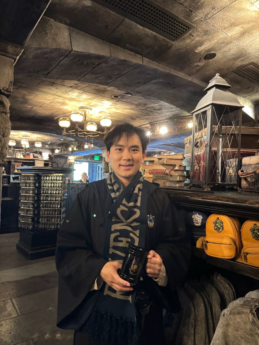 In a wizard robe and scarf, holding a mug